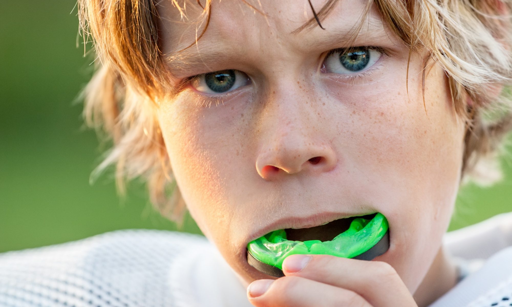 A kid putting a mouth guard in to show their importance against dental damage for athletes